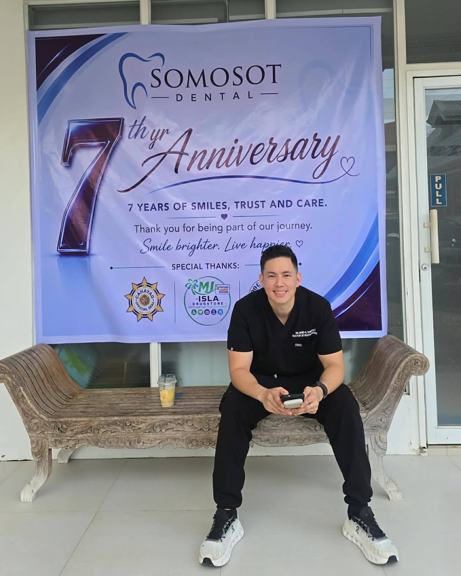 Dr. Jared Somosot seated in front of the Somosot Dental seventh-anniversary banner